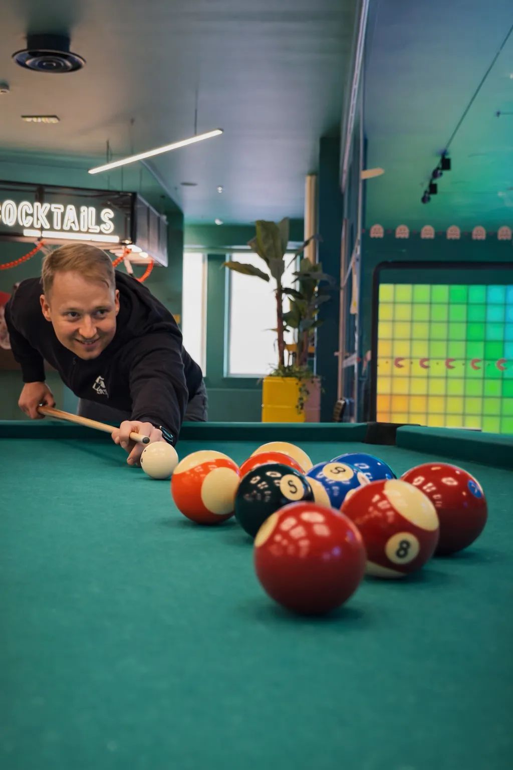 A man smiling while playing billiards alone.