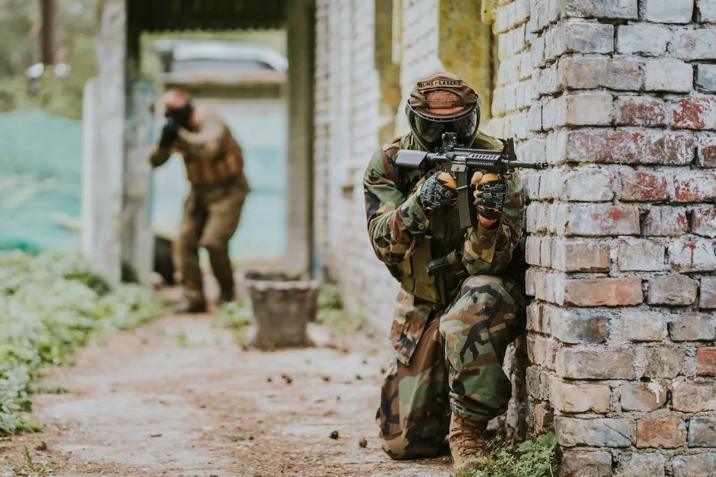 Spēlē airsfotu, cilvēks kamuflāžas drēbēs ar airsoft ieroci