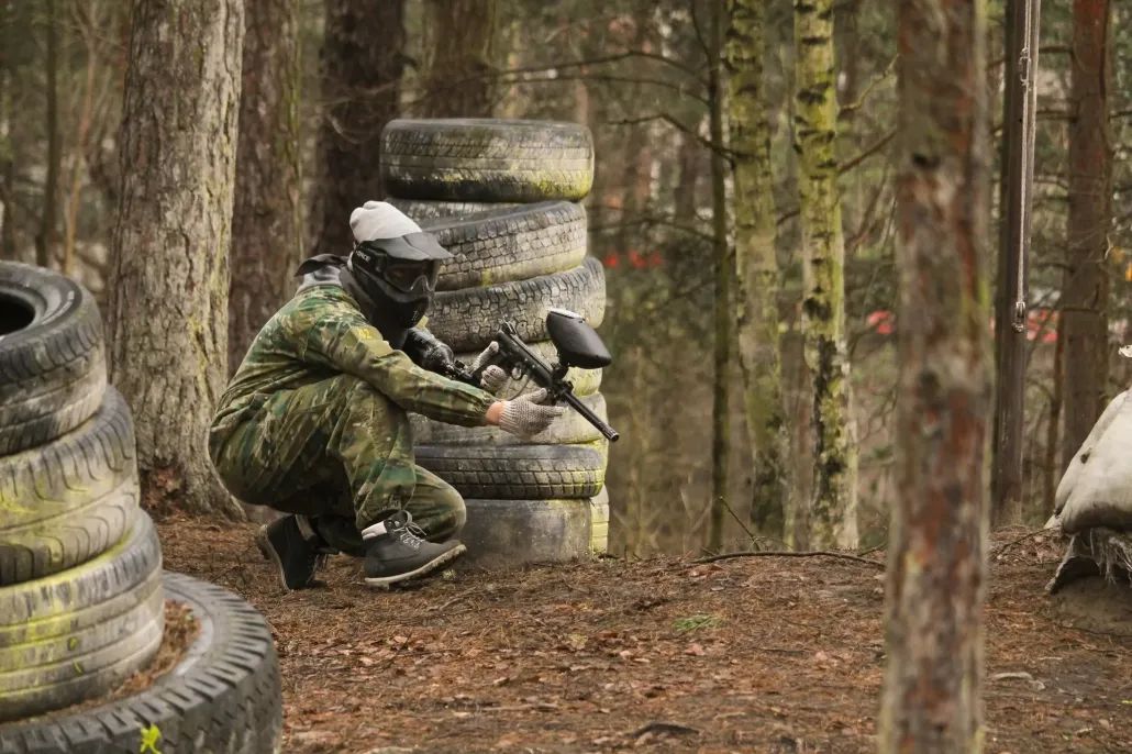 PIE RIEPU KONSTRUKCIJAS MEŽĀ SĒZ SPĒLĒTĀJS AR PEINTBOLA EKIPĒJUMU