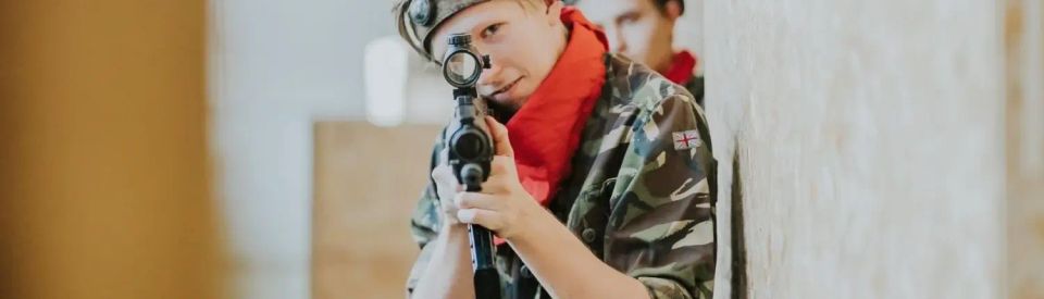 PUISIS TĒMĒ AR LASERTAG IEROCI KAMERĀ UN UZ KAKLA SARKANS LAKATIŅŠ