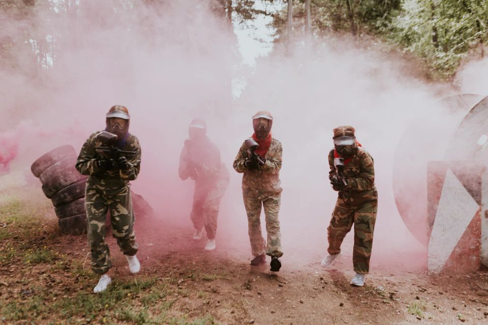 draugi spēlē peintbolu mežaparka āra laukumā