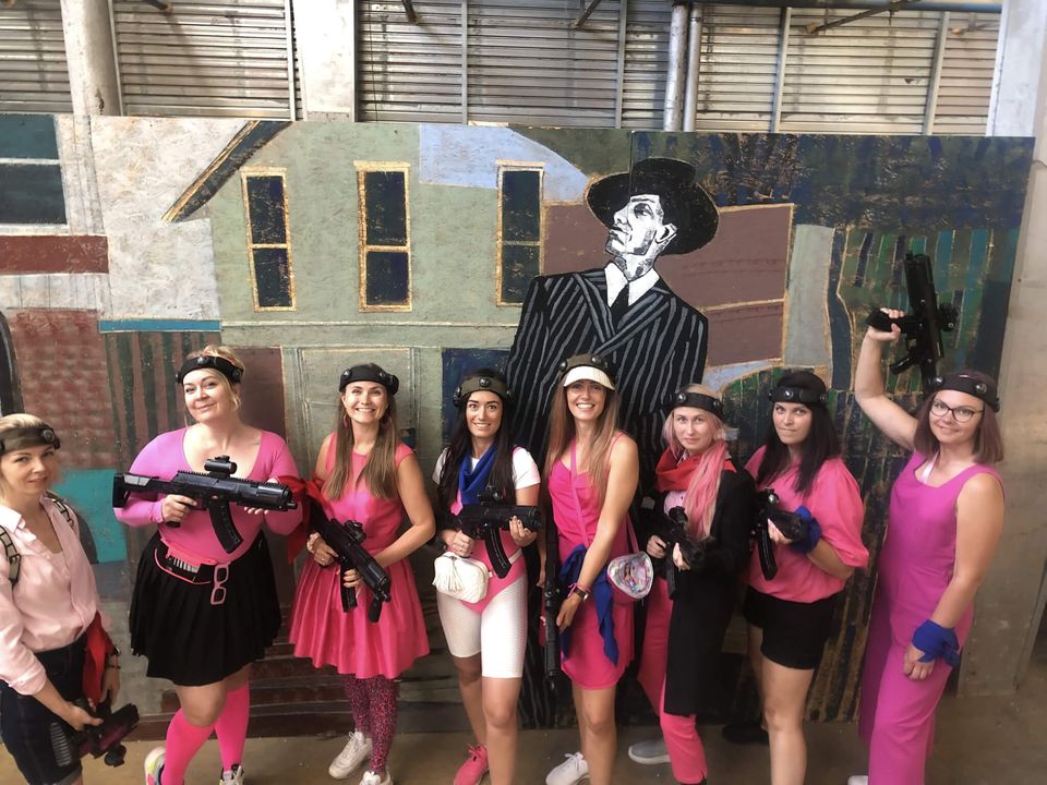 A bachelorette party group wearing pink outfits and laser tag gear.