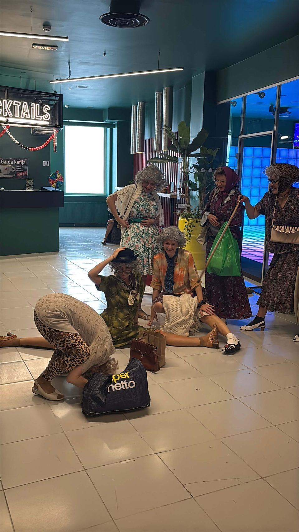 A bachelorette party group striking wild and funny poses at the GUNSnLASERS reception desk in Galerija Centrs.