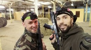 Divi vīrieši iekštelpās ar lāzertag ieroci smaida