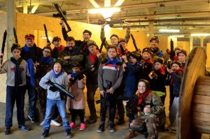 Jaunieši un pieaugušie pozē ar lāzertag ieročiem Juglas lāzertag parkā.