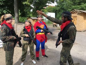 Indietis stāsta 3 latviešiem stratēģiju lāzertagā, visi saģērbušies kamuflāžas drēbēs un viens supermena tērpā